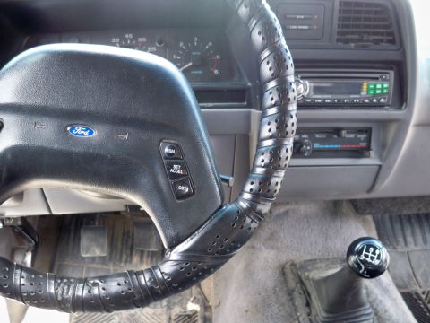 1994 Ford Explorer - The interior of a 1994 Ford Explorer, its steering wheel and manual transmission shifter.