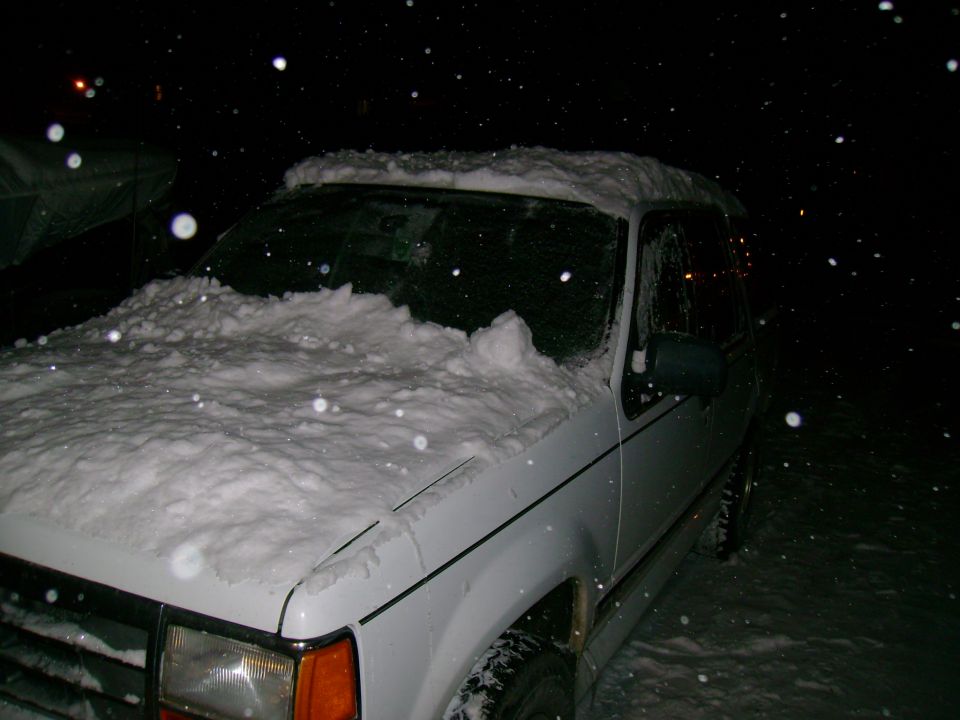 1994 Ford Explorer covered in snow at night, front passenger side visible