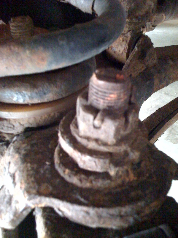 Close-up of rusty suspension part with a castle nut and bolt