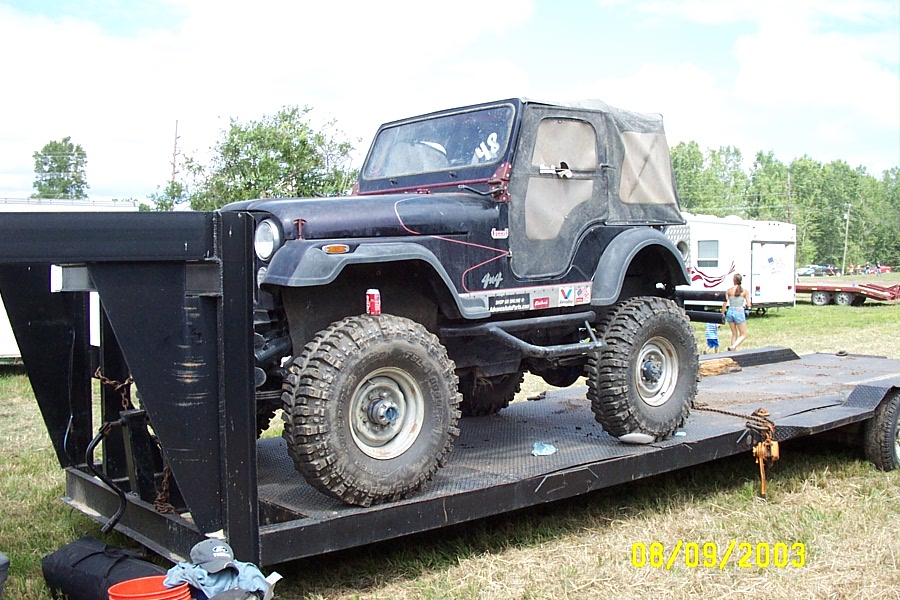 Jeep CJ-7 on a flatbed trailer, with a soft top and off-road tires