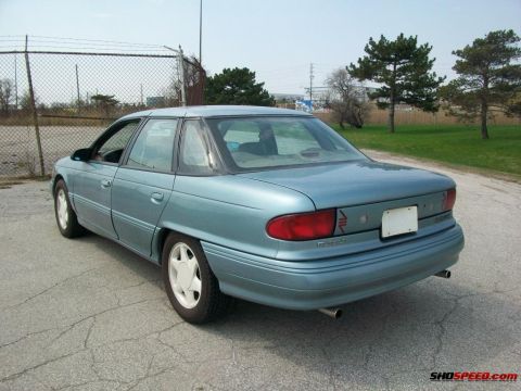 1993 Ford Taurus - 1993 Ford Taurus sedan seen from the rear in an outdoor parking area.