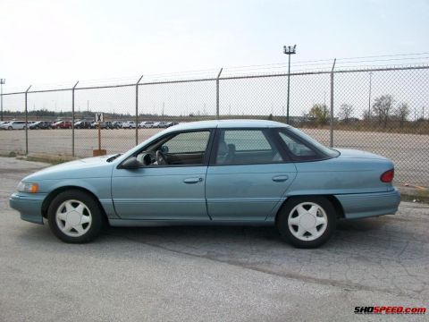 1993 Ford Taurus - This sedan is parked in an outdoor lot with a chain-link fence in the background.