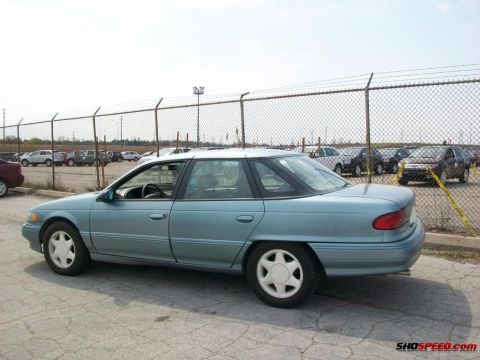 1993 Ford Taurus - A light blue sedan is parked in a lot, with other vehicles visible in the background.