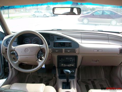 1993 Ford Taurus - Interior view of a tan cabin a Mercury steering wheel and dashboard with an "All Aluminum Body" sticker on the radio.