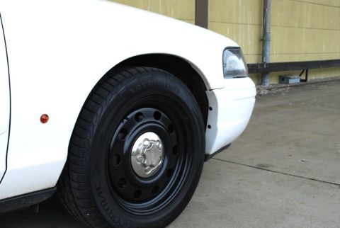 1998 Ford Crown Victoria - Close-up of the front wheel and fender of a white 1998 Ford Crown Victoria.