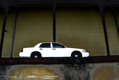 1998 Ford Crown Victoria - A white 1998 Ford Crown Victoria sedan is seen from the side, parked on a ledge.