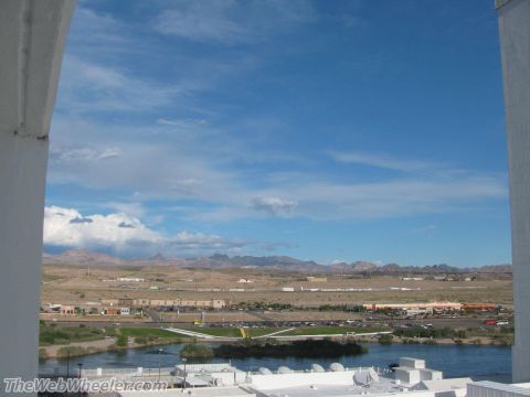 1996 Ford C-350 (Centurion Conversions) - View of a desert landscape with a river and buildings under a blue sky with clouds.