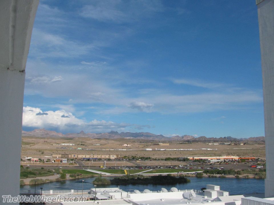 Desert landscape with a river in the foreground and mountains in the distance, viewed through an archway