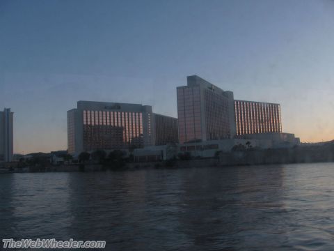 1996 Ford C-350 (Centurion Conversions) - A wide shot shows a large hotel complex situated on the waterfront, with the sky transitioning from day to night.