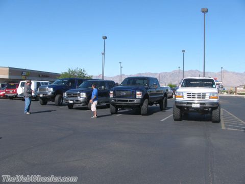 1996 Ford C-350 (Centurion Conversions) - Multiple pickup trucks are parked in a lot under a clear blue sky.