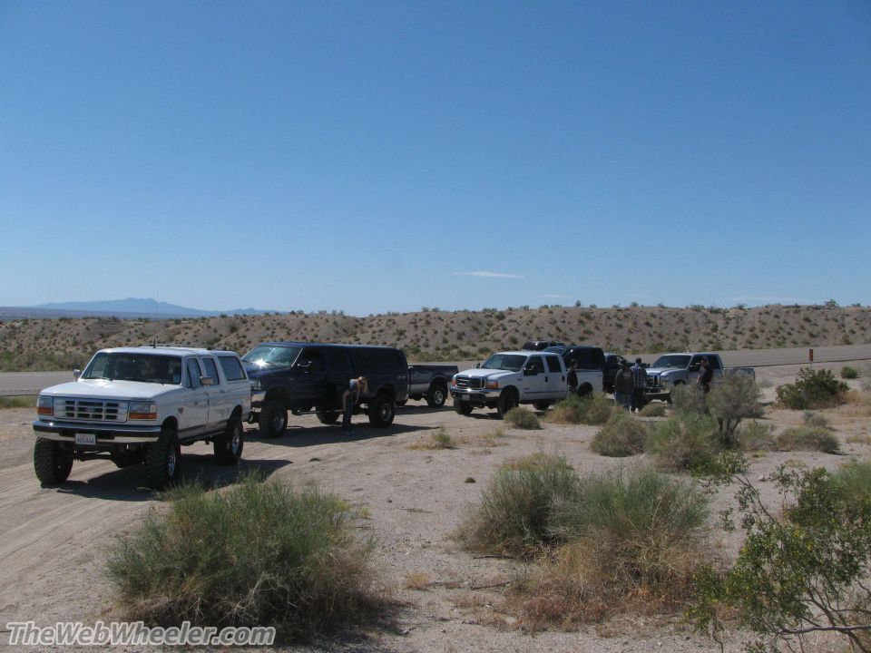 White Ford Bronco with lifted suspension and large tires, parked on a dirt road