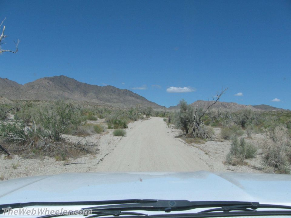 White dashboard and windshield view of a desert road with mountains in the background