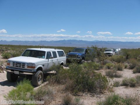1996 Ford C-350 (Centurion Conversions) - A white 1996 Ford C-350 Centurion Conversions SUV is seen in a desert landscape with other vehicles behind it.