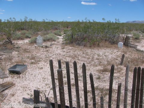 1996 Ford C-350 (Centurion Conversions) - A desolate cemetery scene in the desert, marked by old tombstones and a weathered wooden fence.