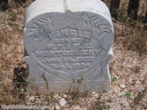 1996 Ford C-350 (Centurion Conversions) - A white marble gravestone stands in a dry, grassy cemetery, bearing carved inscriptions.