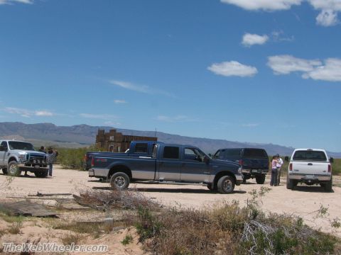 1996 Ford C-350 (Centurion Conversions) - Several trucks and an SUV are parked in a dry, open area with mountains visible in the distance.