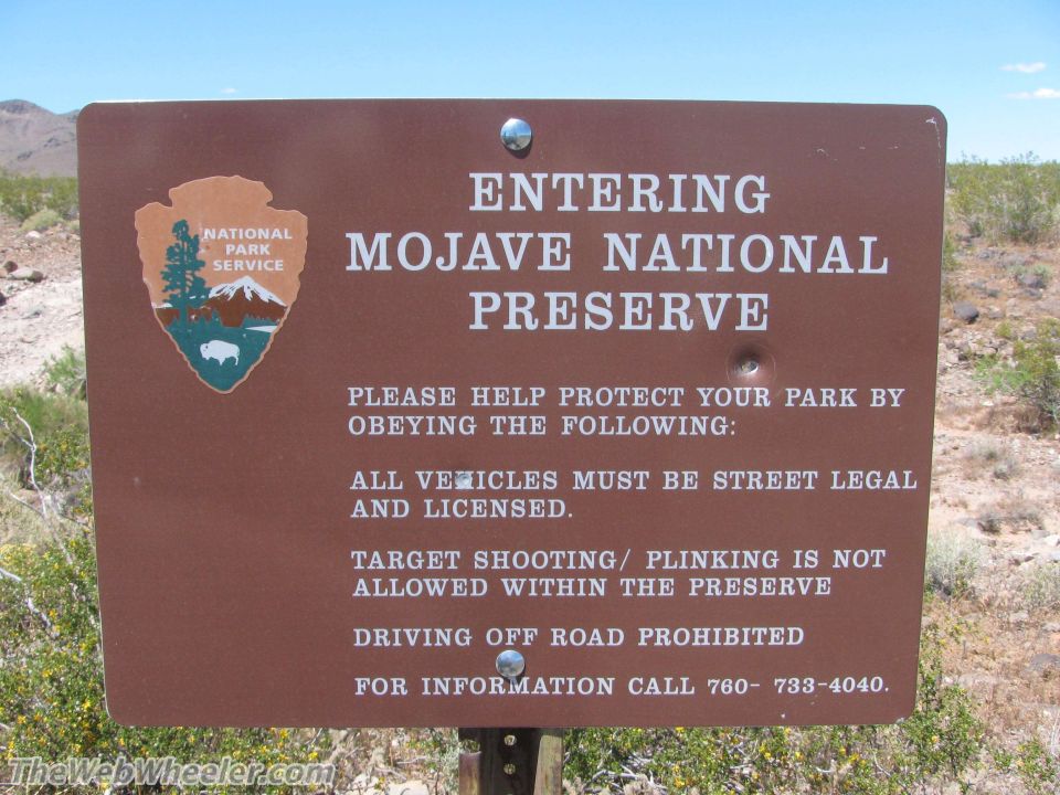 Sign for Mojave National Preserve with rules about vehicles, shooting, and off-road driving. Includes National Park Service logo