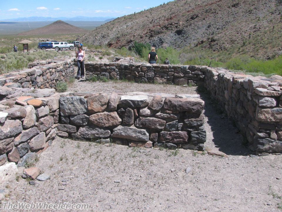 Stone ruins with two SUVs and people in the background