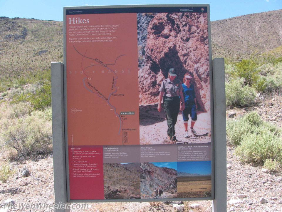Information sign with map and photos about hikes in a desert landscape