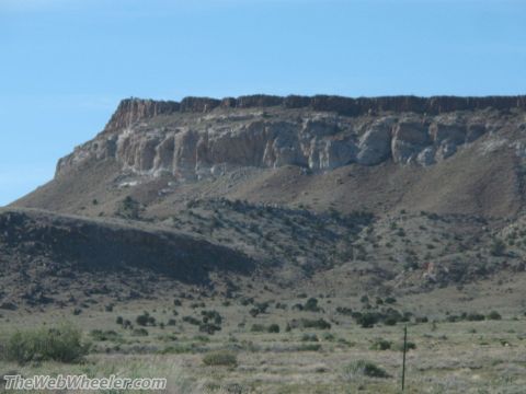1996 Ford C-350 (Centurion Conversions) - A vast desert landscape unfolds, dominated by a towering mesa under a clear blue sky.