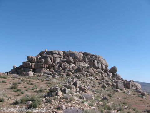 1996 Ford C-350 (Centurion Conversions) - A rocky hill with sparse vegetation under a clear blue sky, likely taken in a desert environment.