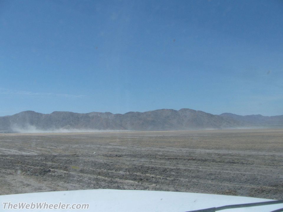 View of a dry, dusty plain with mountains in the distance under a clear blue sky