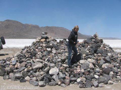 1996 Ford C-350 (Centurion Conversions) - A person stands near rock cairns in a desert landscape with a vehicle's rear visible.