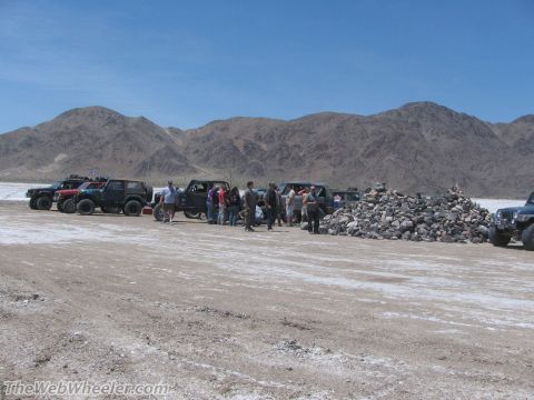1996 Ford C-350 (Centurion Conversions) - Group of off-road vehicles and people gathered in a desert landscape with mountains in the background.