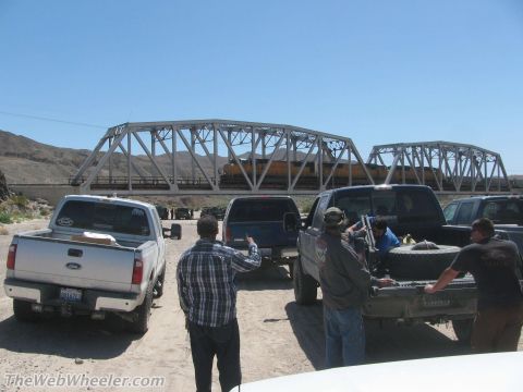 1996 Ford C-350 (Centurion Conversions) - Several trucks are parked near a train bridge on a sunny day.