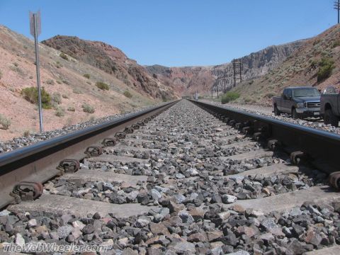 1996 Ford C-350 (Centurion Conversions) - Two trucks are parked next to railroad tracks in a remote desert area under a clear blue sky.