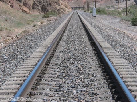 1996 Ford C-350 (Centurion Conversions) - Railroad tracks lead through a desert landscape, with mountains in the background and utility poles lining the right side.