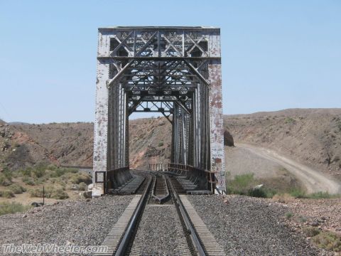 1996 Ford C-350 (Centurion Conversions) - A railroad bridge spans a desert landscape under a clear blue sky.