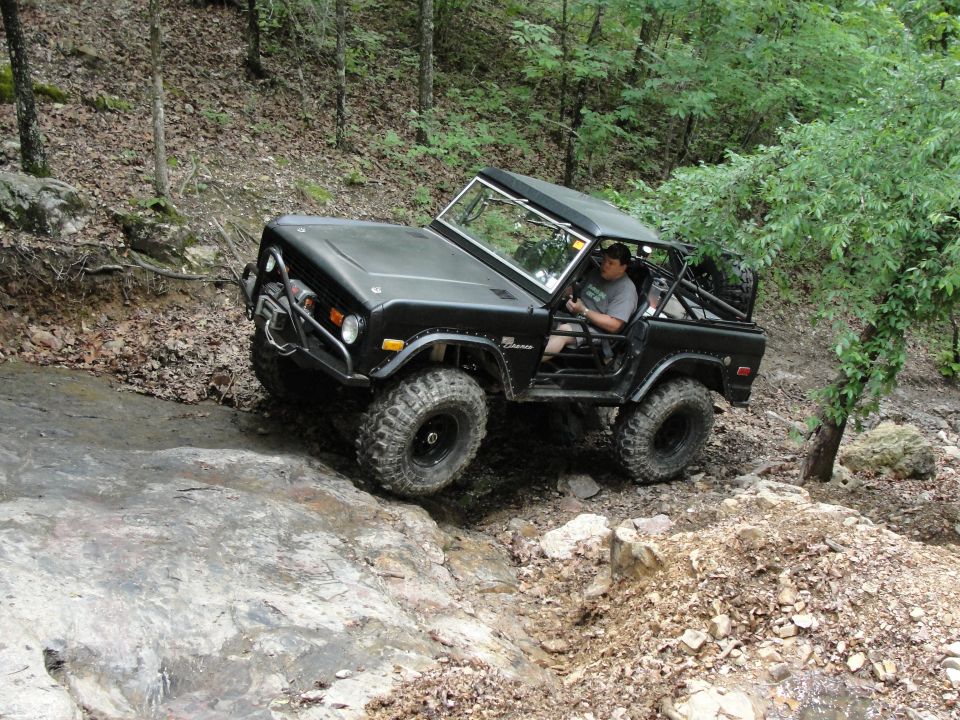 Black Ford Bronco off-roading on a rocky trail, with a driver inside