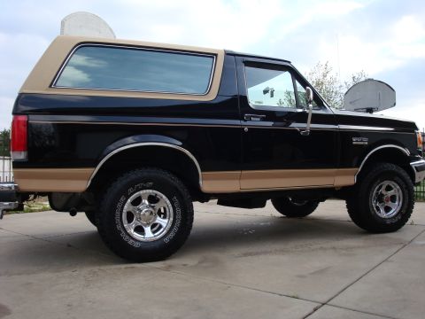 1989 Ford Bronco - This two-tone Ford Bronco is viewed from the side, revealing its classic SUV profile and aftermarket wheels.