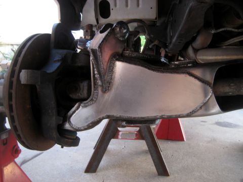 1996 Ford Bronco - Close-up of a custom-welded metal part installed on a vehicle's front suspension system.