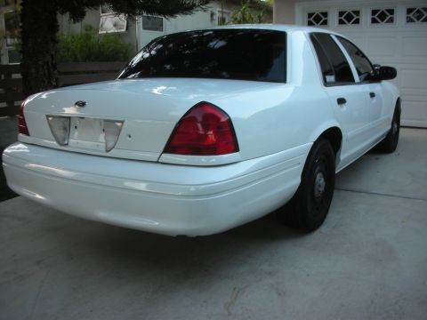 2004 Ford Crown Victoria - Rear view of a white 2004 Ford Crown Victoria sedan parked in front of a garage.
