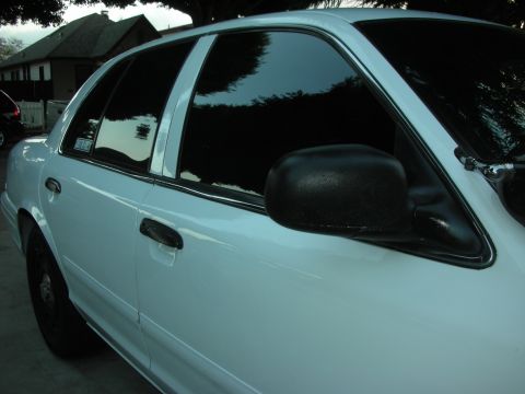 2004 Ford Crown Victoria - Side profile of a white 2004 Ford Crown Victoria with tinted windows and black side mirrors.