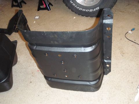 1995 Ford Bronco - A close-up view of a black plastic fender liner, likely for a vehicle, resting on a concrete floor.