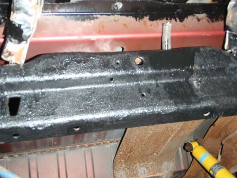 1995 Ford Bronco - Close-up of a vehicle's undercarriage, showing the gas tank and a yellow Bilstein shock absorber.