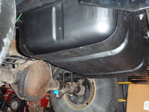 1995 Ford Bronco - Underside view of a vehicle's black metal gas tank and rear axle assembly.