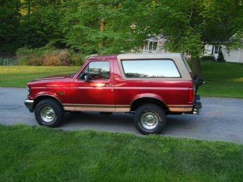 1995 Ford Bronco - This red 1995 Ford Bronco features a tan removable top and is shown from the side.