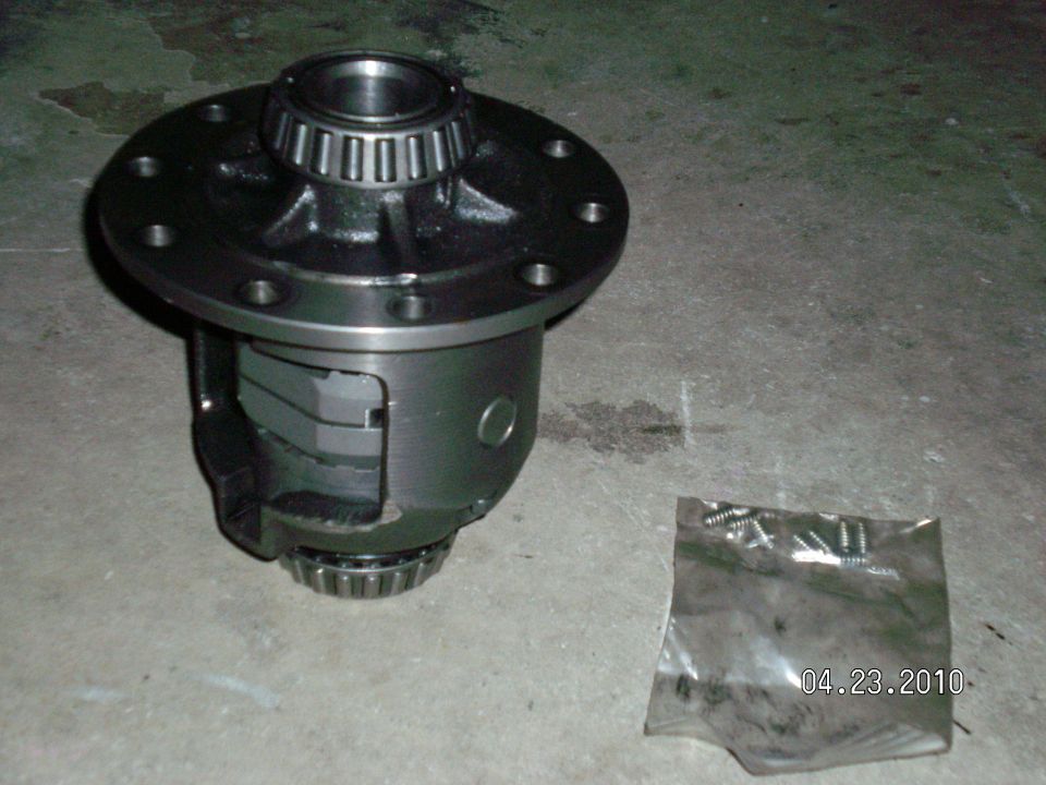 Differential carrier with bearings and a bag of screws on a concrete floor