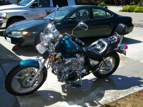 1992 Yamaha Virago - A teal motorcycle is parked on a concrete driveway next to a dark green sedan and a silver truck.