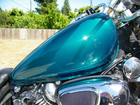 1992 Yamaha Virago - Close-up of a teal motorcycle fuel tank and engine details under a sunny sky.