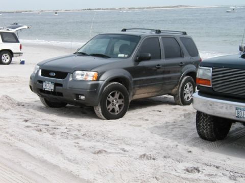 1994 Ford Bronco - A Ford Escape and other vehicles are parked on a sandy beach near the ocean.