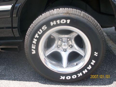 1993 Mercury Grand Marquis - Close-up of a wheel and tire on a black vehicle, showing custom rims and tire branding.