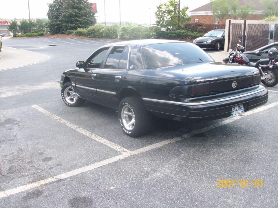Black Mercury Grand Marquis sedan rear 3/4 view in a parking lot