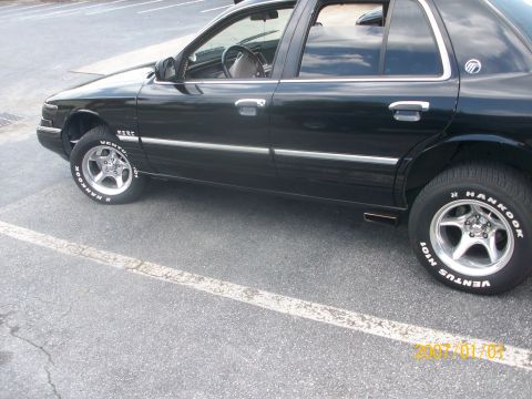 1993 Mercury Grand Marquis - Side profile of a black 1993 Mercury Grand Marquis with custom wheels.