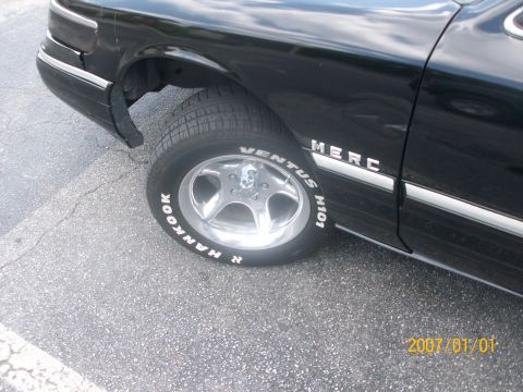 1993 Mercury Grand Marquis - A black sedan is shown from the side, focusing on the front wheel and fender area with visible tire and body trim details.