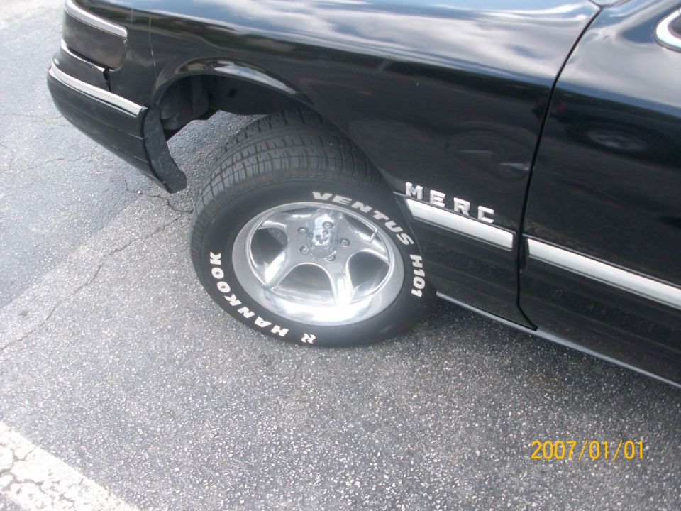 Black car front wheel with polished 5-spoke alloy and Hankook white-letter tire